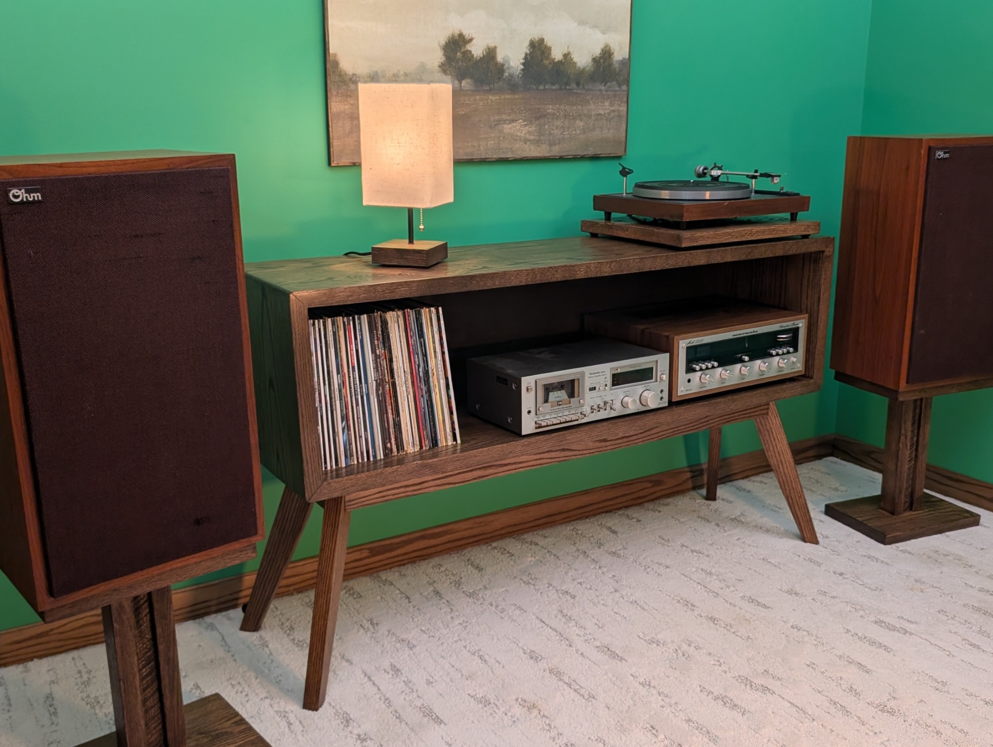 Oak console holding records, vintage audio components and a turntable, framed by speakers